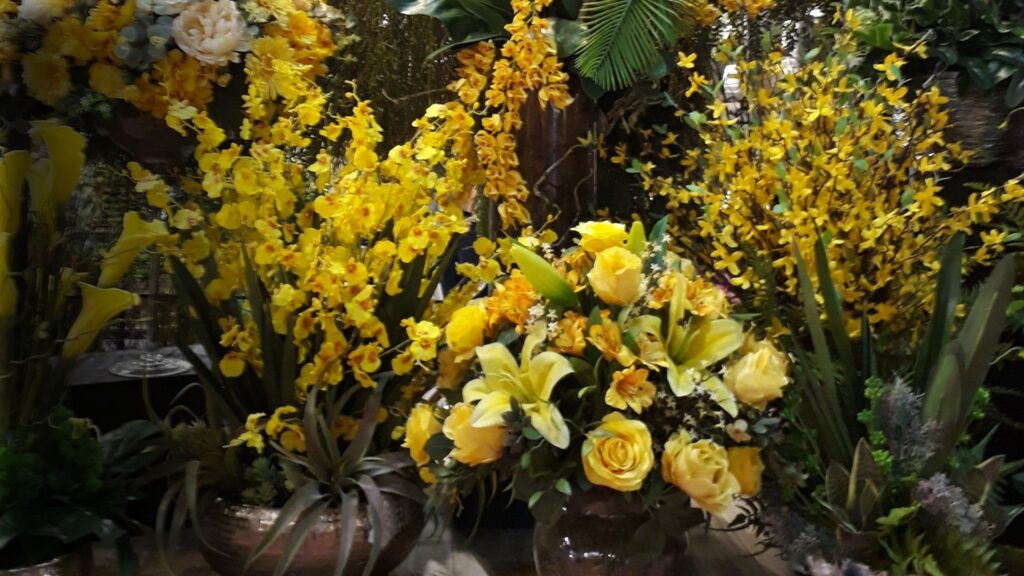 Composição de flores artificiais na cor amarela com folhagens artificiais verde